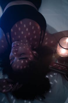 Woman lying under warm candlelight, creating a peaceful ambiance with soft patterns.