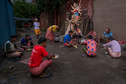 Group of artisans taking a meal break near a Durga sculpture on a street in India.
